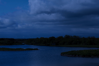 A night time image of a nature reserve with a lake and trees.